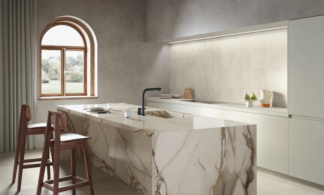 A modern kitchen featuring a striking Calacatta Royal porcelain slab island with waterfall edges. The slab showcases a white background with elegant gray, deep charcoal, and soft burgundy veining, adding depth and sophistication. Sleek cabinetry, contemporary lighting, and high-end appliances enhance the luxurious and refined aesthetic of the space.