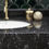 Thumbnail: A close up of black sea quartz showing the black countertop, white sink and rustic gold hardware
