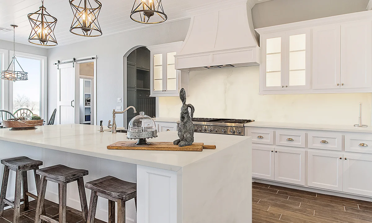Onyx White kitchen featuring the island top made of porcelain and the countertops. The stone shocases creamy and warm tones in a neutral and warm setting in stone slabs.