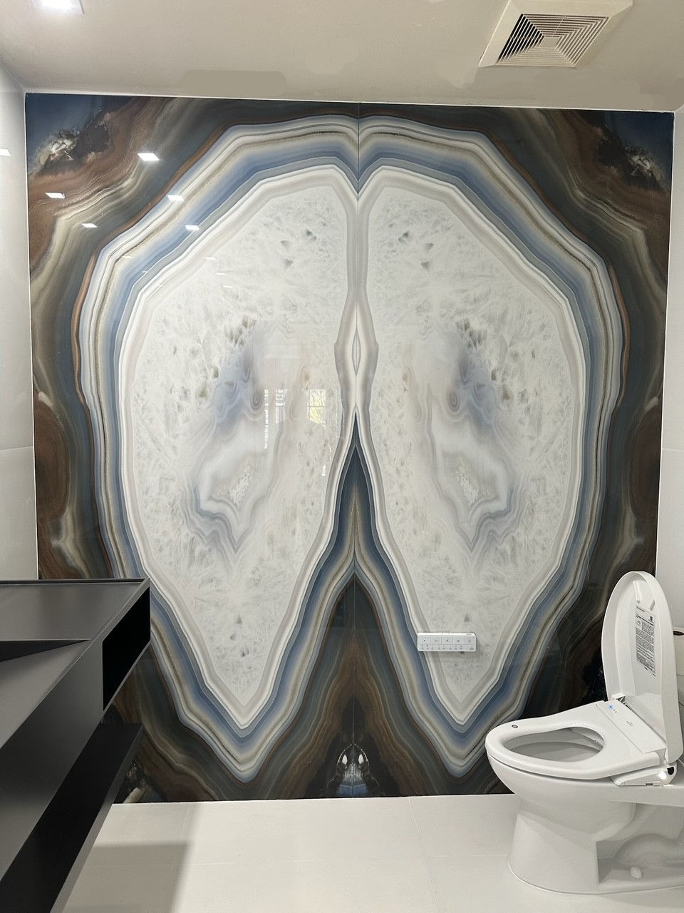 Modern guest bathroom featuring two geode look porcelain slabs book-matched on the accent wall creating dramatic appeal