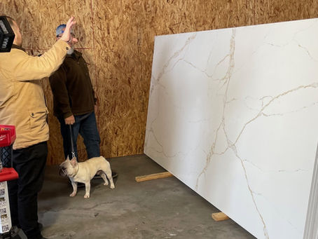 Customers viewing a large white quartz slab with gold Calacatta-style veining under adjustable lighting at Verona Quartz Surfaces’ slab yard in Sun Valley, Los Angeles, California.