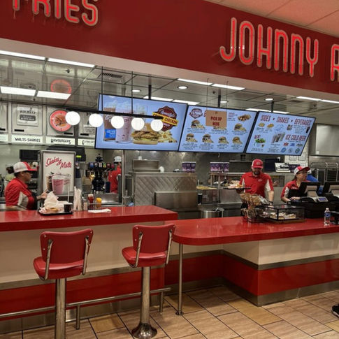 The ordering desk at Johnny Rockets features big frontage and a vintage and retro style. The bright red theme, including the red countertops grab attention and boast a innovative theme to fast food dining. 