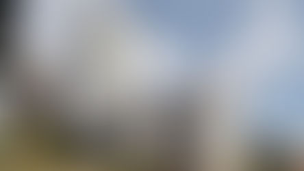 Moderne højhuse med mønstret facade under blå himmel med skyer.