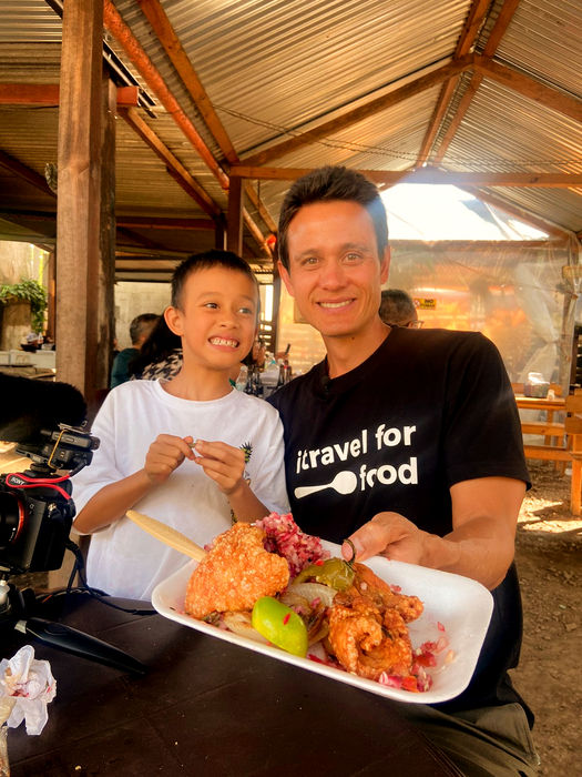 A traveler and a child share a traditional Guatemalan dish in a local setting during a culinary tour. A heartwarming moment that reflects how food connects generations and plays an essential role in Guatemala’s everyday life and cultural traditions.