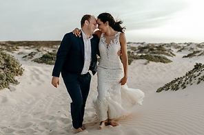 2 Happy bride and groom embracing on a sandy beach at dusk