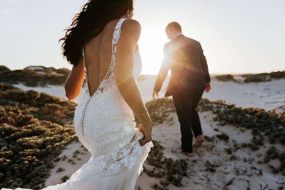 9-A bride wearing a backless lace dress and her groom walk on sand dunes in Mexico during