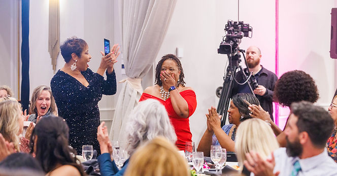 Jacquie J being recognized at a conference, receiving a round of applauce from attendees.