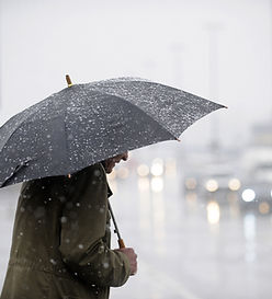 man with umbrella crossing the road in the rain