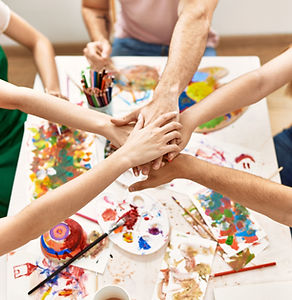 a group of hands joining over a painted canvas