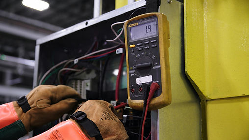 Planned preventative maintenance showing electrician carrying out electrical testing on fuse board on site
