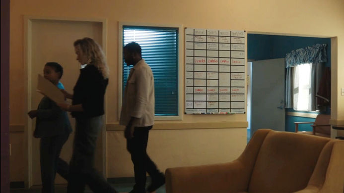 Community center interior set with foosball table, scheduling board, and group scene staged for television production.