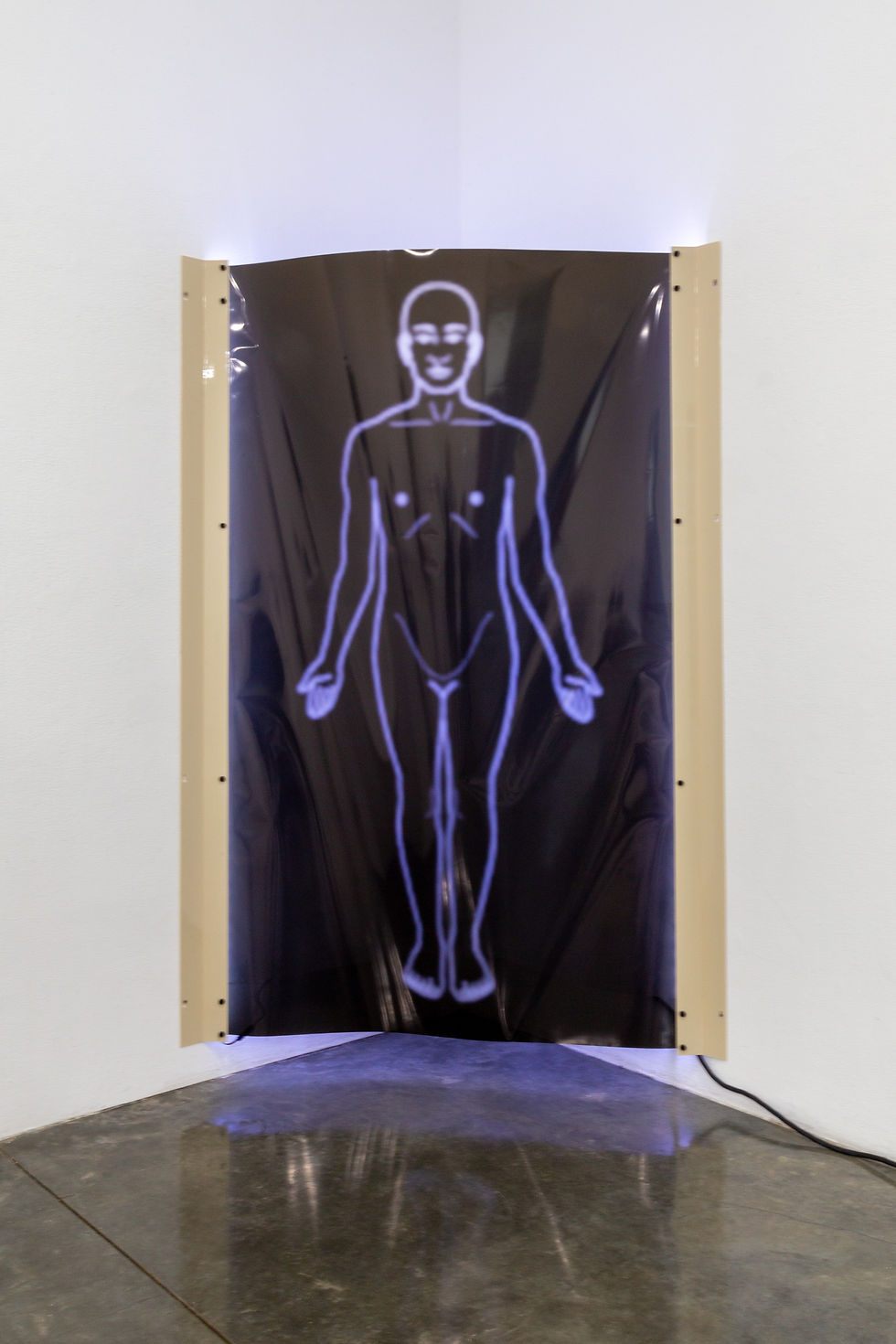 The image shows a slightly larger than life-size graphic outline of a human body on a flexible black shiny surface, hung in the corner of a gallery with white walls, suspended perhaps a foot above the floor. There is a purple light behind the piece, which shines through the outline.