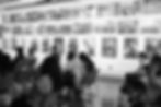 Diverse audience seated with many photographs exhibited on the wall