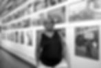 Shawn Batey standing in front of many photographs hung on the wall