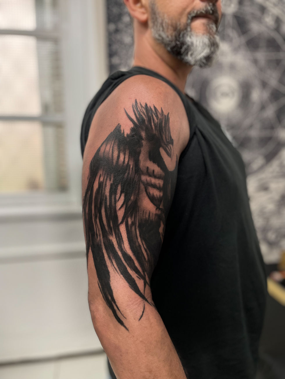 Homem com tatuagem Blackwork de asa escura detalhada no braço.