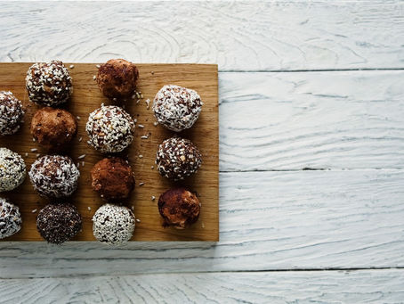 A selection of handmade chocolates on a wooden board on a white table