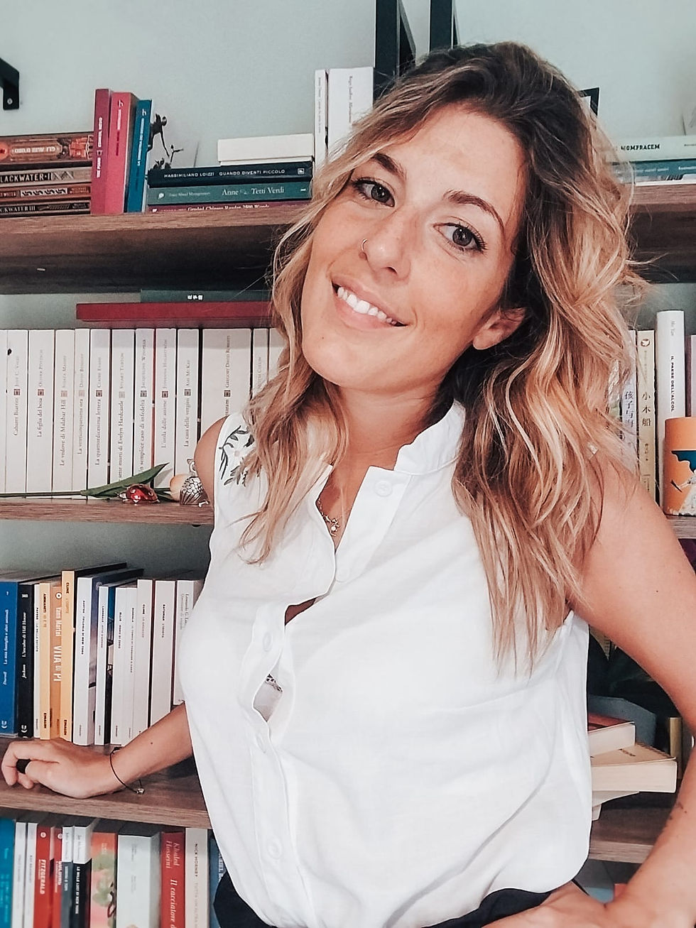 ragazza bionda davanti a una libreria, pila di libri