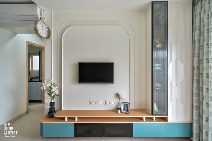 Modern TV entertainment unit featuring a white arched back panel, floating wood shelf, light blue lower drawers, and a vertical glass-door display cabinet.