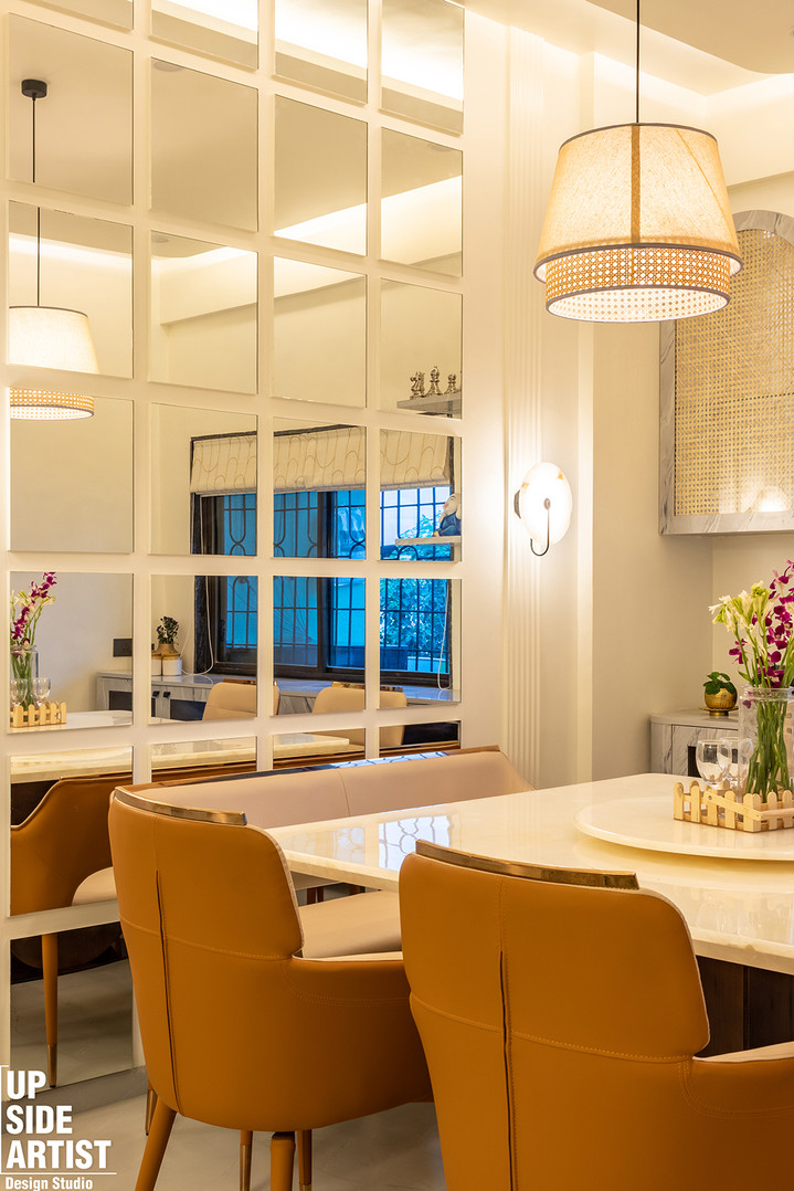 Modern dining table detail showcasing mustard upholstered chairs, a lazy Susan with purple orchids, and a full-height white grid mirror reflecting a window and pendant light.
