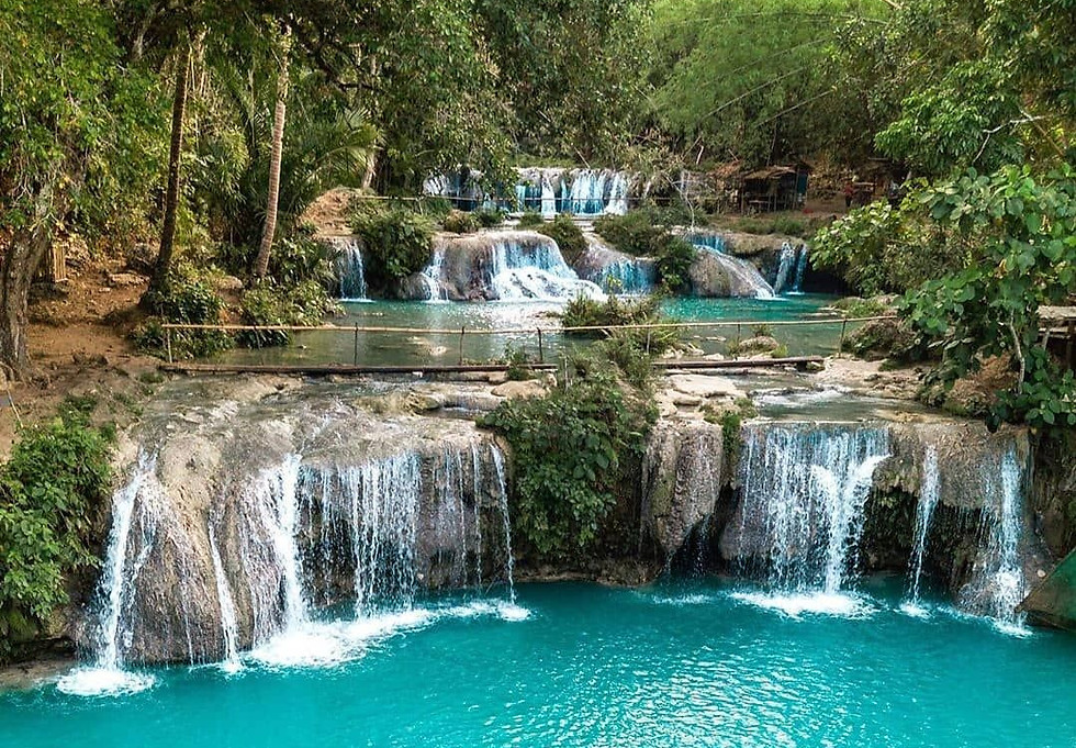 Aerial photograph of Cambugahay Falls, Siquijor, Philippines — tiered cascading waterfalls and a luminous turquoise swimming pool nestled deep within lush tropical forest, a hidden natural destination discovered through a CILYC private sailing expedition
