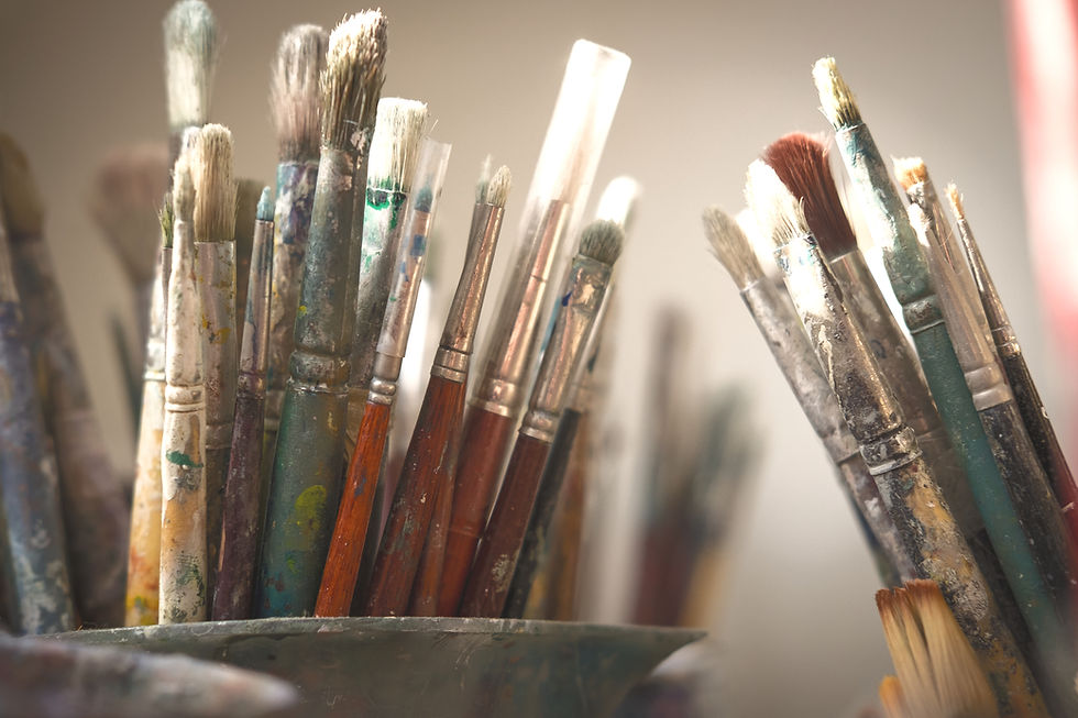 Close-up of paintbrushes in a jar in UK artist Carla Tracy’s studio workspace