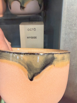 coffee mug from the Nottingham Contemporary shop, featuring a warm peach glaze with deep green and black dripped detailing