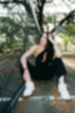 Young woman in black jumpsuit sitting on tennis court