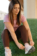 Woman tying shoe for wellness fitness