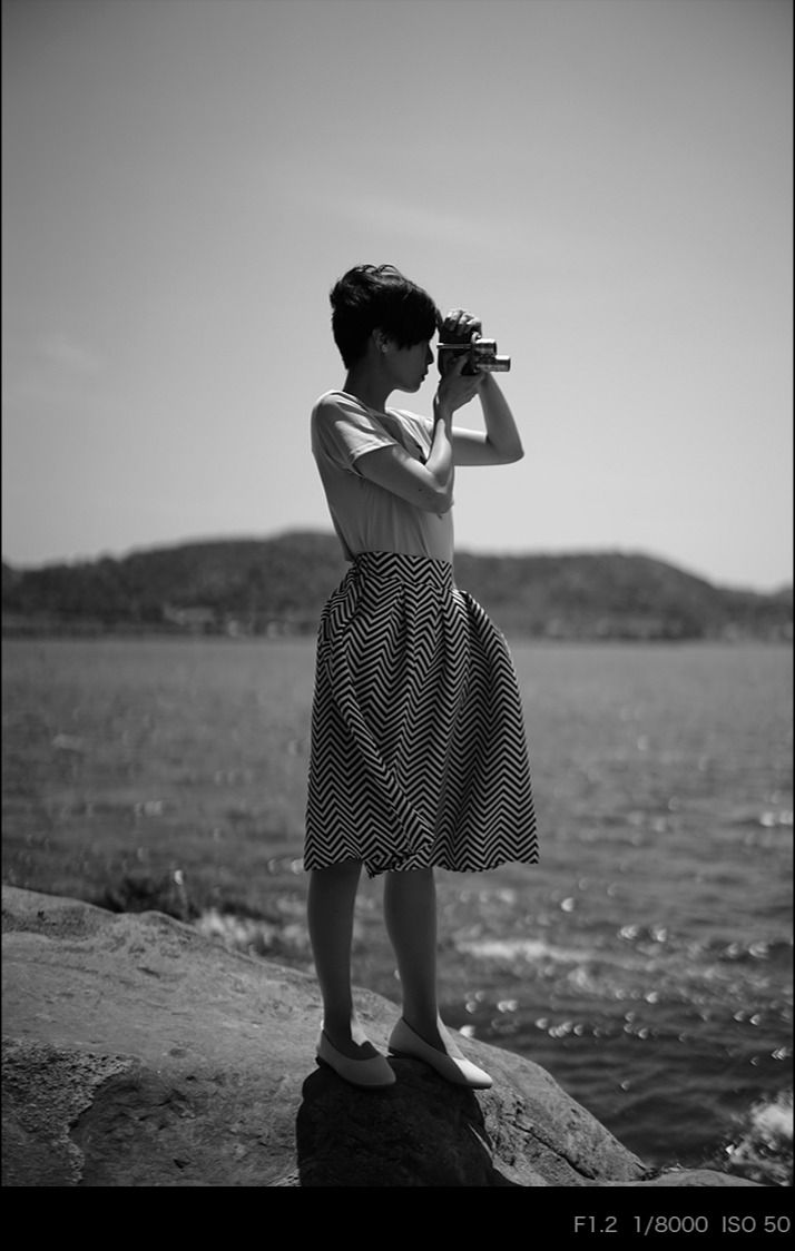 Thumbnail: Woman taking a photo with a SEPTON 40mm F2 lens by a lake.