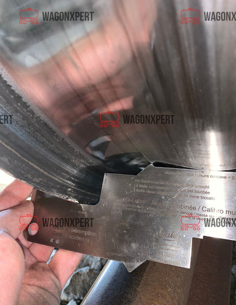 Die Hand hält ein WagonXpert-Messgerät, um die Tiefe des Tanks eines Eisenbahnwagens zu messen.