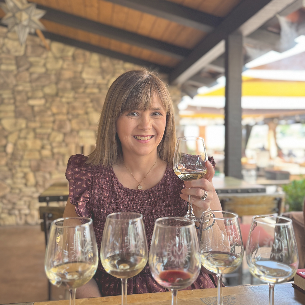 Erin raising a glass of wine at Miramonte Winery, with a flight of wine glasses in front of her