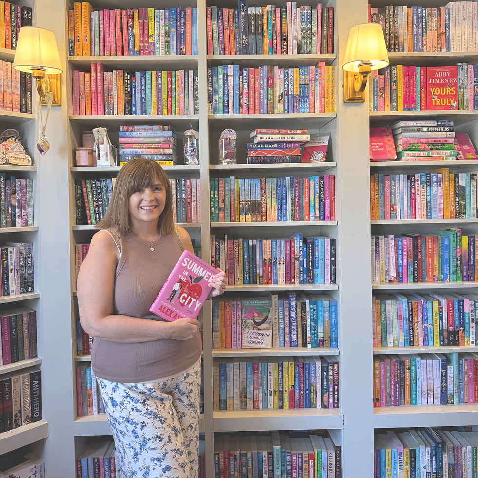 Erin in front of a wall of books at In Bloom Bookery