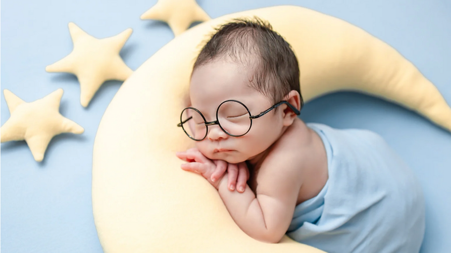 schlafendes Baby liegt entspannt auf einem Halbmondkissen