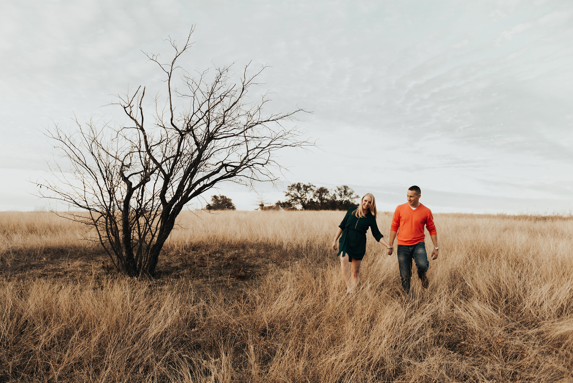 Couple walking hand in hand through tall grass near tree at Winfrey Point Dallas.