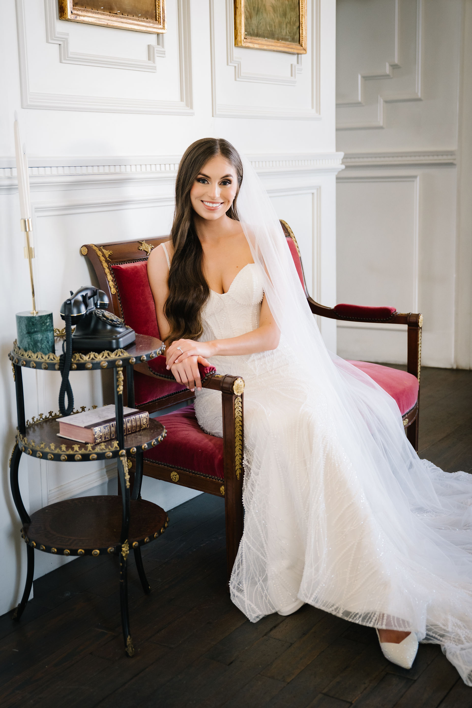 Bride in wedding dress standing beside chair in historic interior at The Mason Dallas during bridal portraits