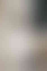 Engagement photo of a couple leaning against stone columns with urban backdrop, modern editorial Dallas engagement photography with romantic city vibes.