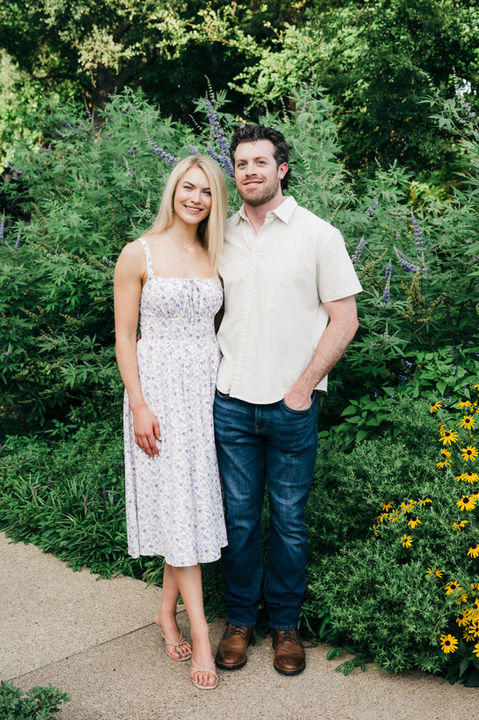 Couple celebrating engagement with smiles in Highland Park garden.