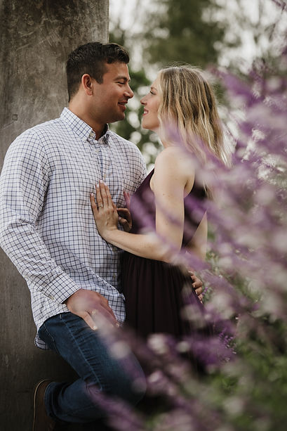 Couple during engagement session surrounded by purple flowers at the Dallas Arboretum