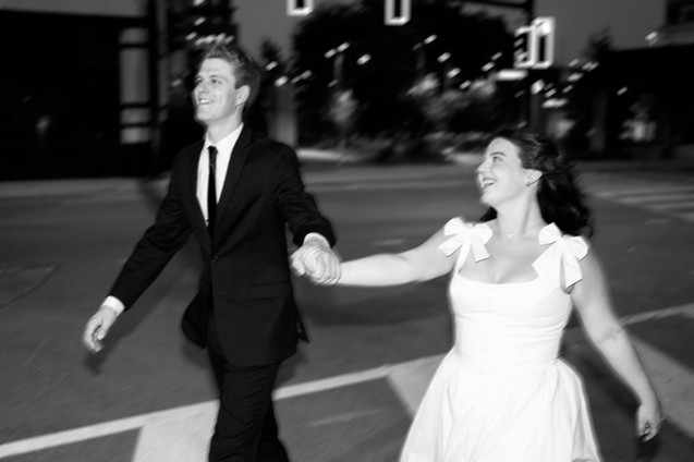Couple holding hands crossing a city street in downtown Dallas engagement session.