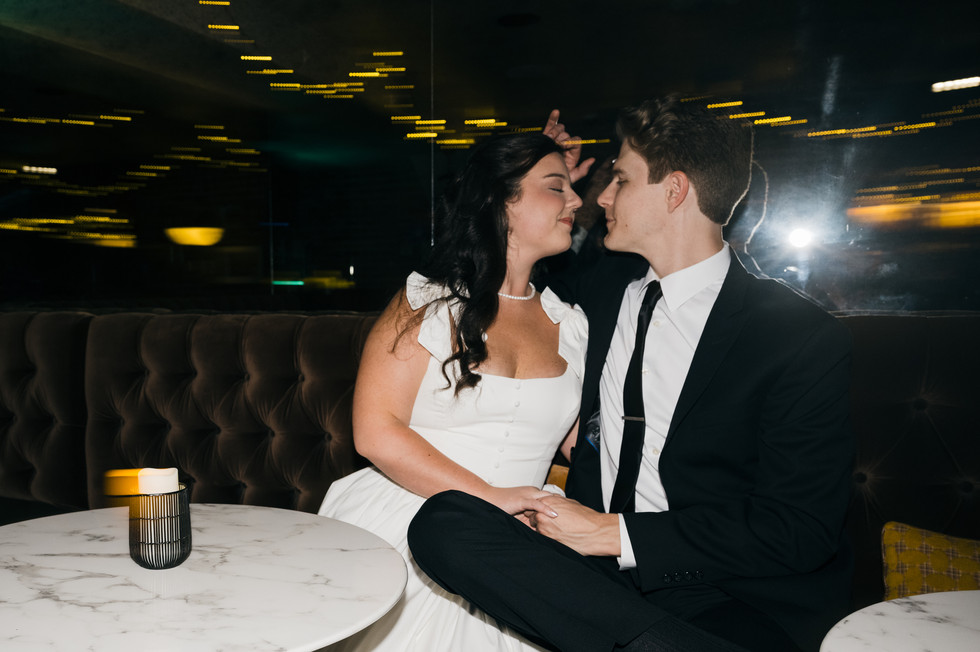Romantic engagement photo in a downtown Dallas lounge with city lights reflecting in the background, modern and moody engagement photography in Dallas.