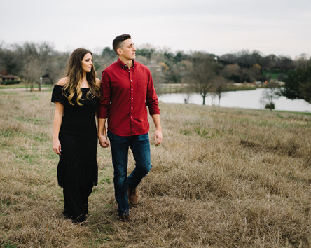 Couple holding hands in open field with White Rock Lake behind them at Winfrey Point.