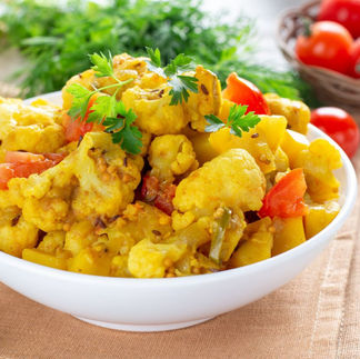 "Gobi aloo in a white dish on a decorated table"