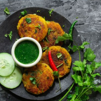 "Aloo Tikki with garnish and green dip"