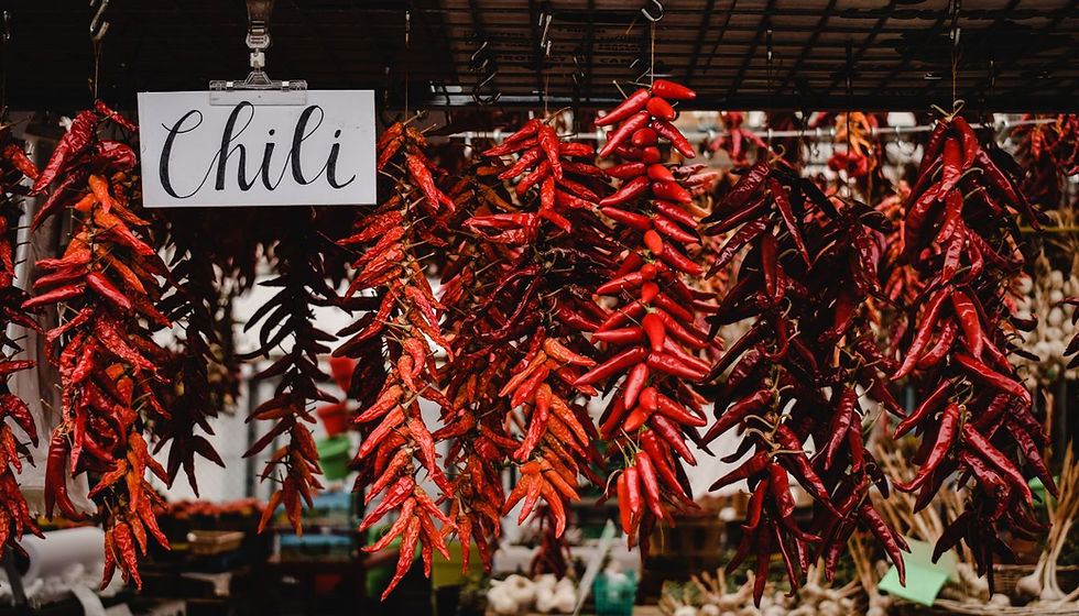 Hanging red chili peppers at a market stall with a sign reading Chili, creating a vivid, spicy display.