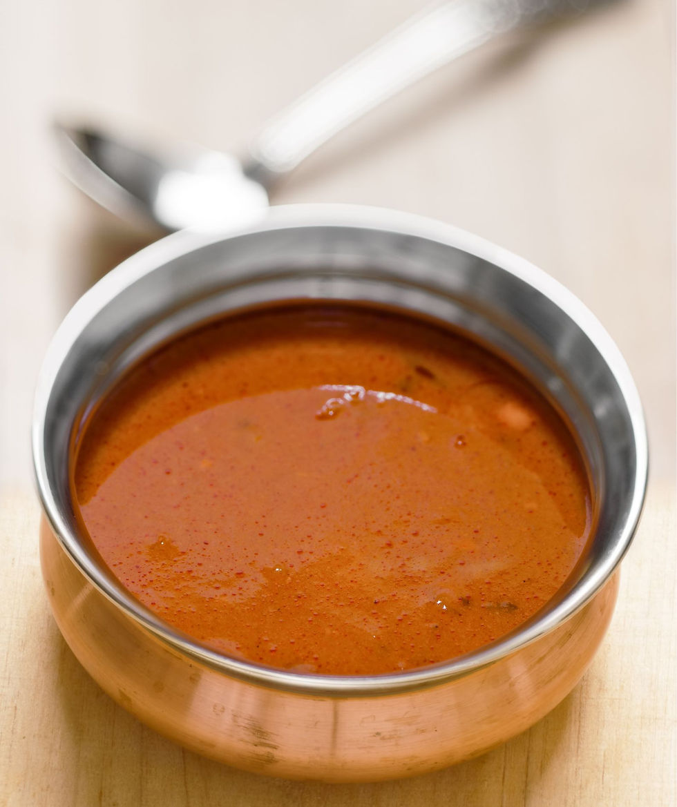 Copper bowl with rich, Mulligatawny soup on wooden surface. Shiny spoon in the blurred background. Warm and inviting atmosphere.