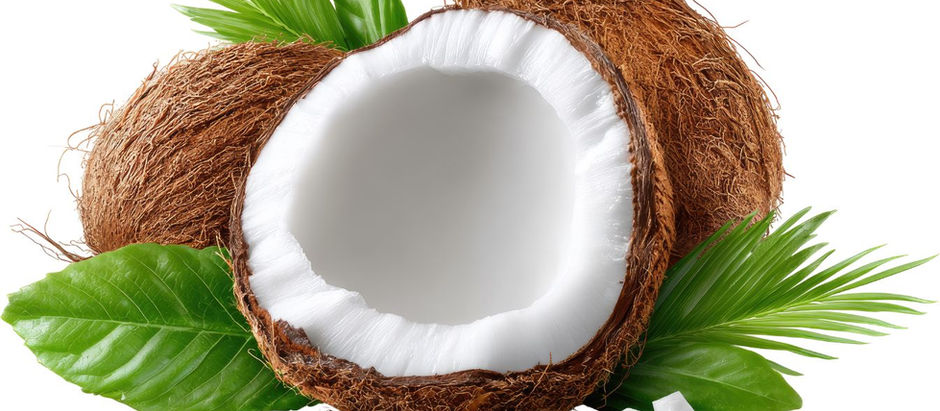 A halved coconut with white flesh and brown shell is surrounded by green leaves on a bright background, conveying a tropical feel.