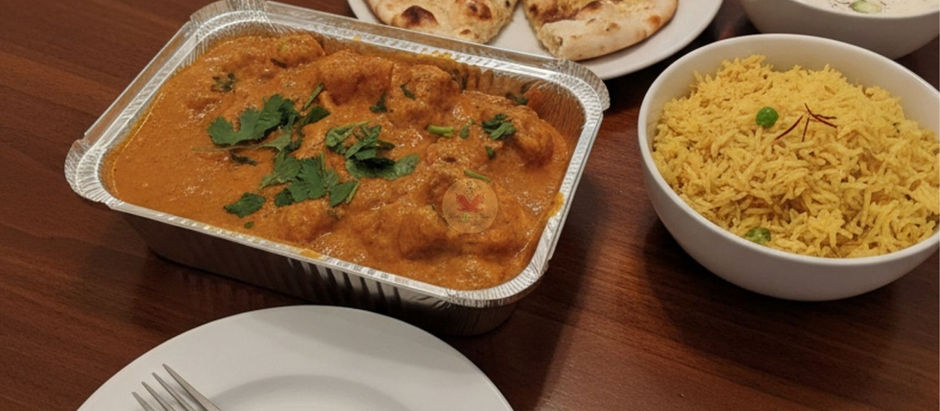 Takeaway Chicken Korma on wooden table: chicken korma, naan, rice, and yogurt. Text: Bir Chicken Korma, Take away style, Stevie’s Curry Magic.