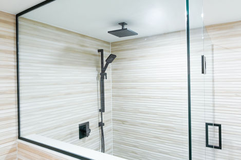 Walk-in shower with black-framed glass partition and matte black rainfall showerhead in a Vaughan renovation.