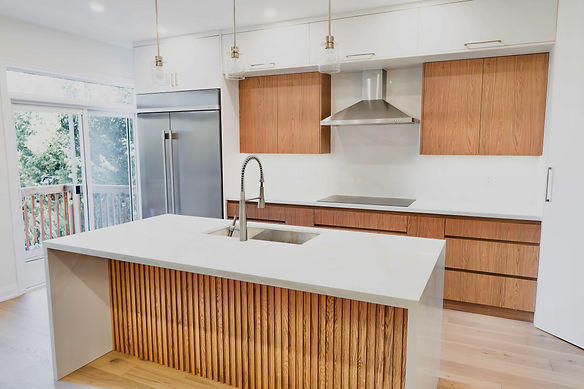Kitchen renovation with white oak and white cabinetry, stainless steel KitchenAid appliances, and solid surface finishes.
