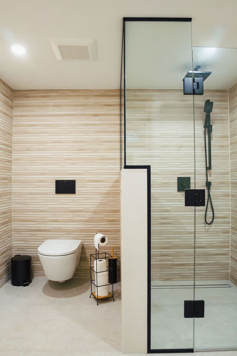 View of a renovated Vaughan bathroom with a floating toilet and a black-framed glass shower partition.